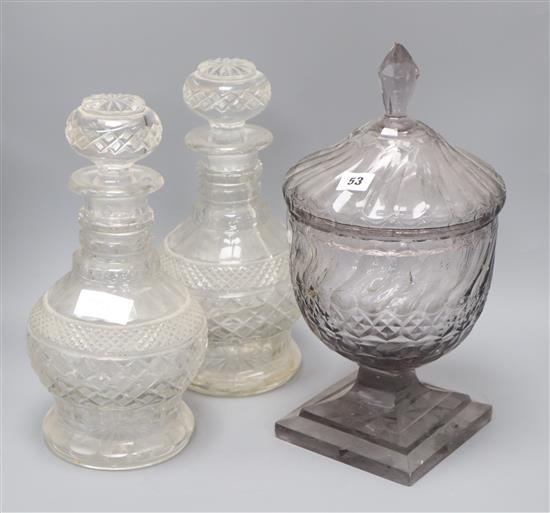 A pair of cut glass decanters and a cut glass lidded pedestal jar height of tallest 40cm
